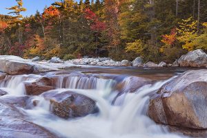 Multi-coloured fall foliage along the Swift River Lower Falls, White Mountain National Forest in New Hampshire, USA.